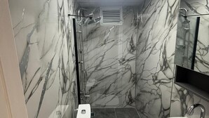 A bathroom with a toilet, sink, and shower area, featuring marble walls and a skylight. - Klas Otel (Karasu)