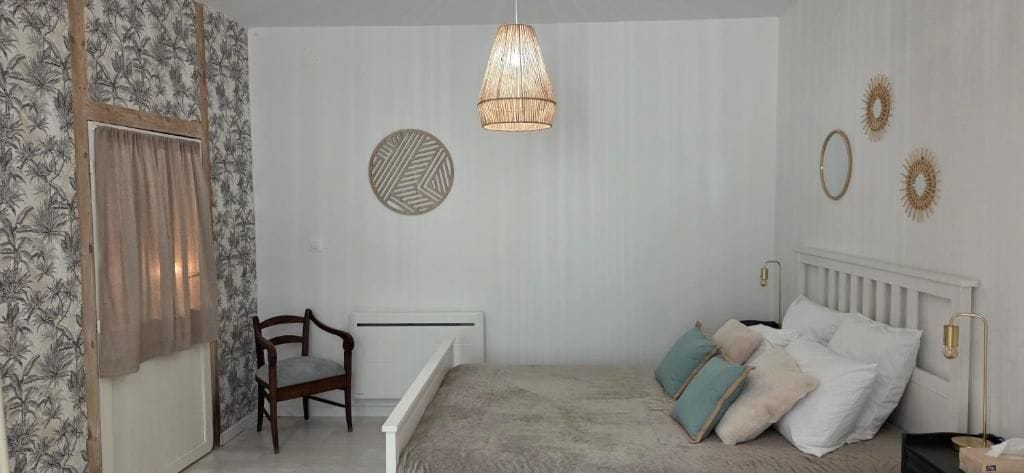 A bedroom with a bed, a chair, a radiator, and decorative wall art.