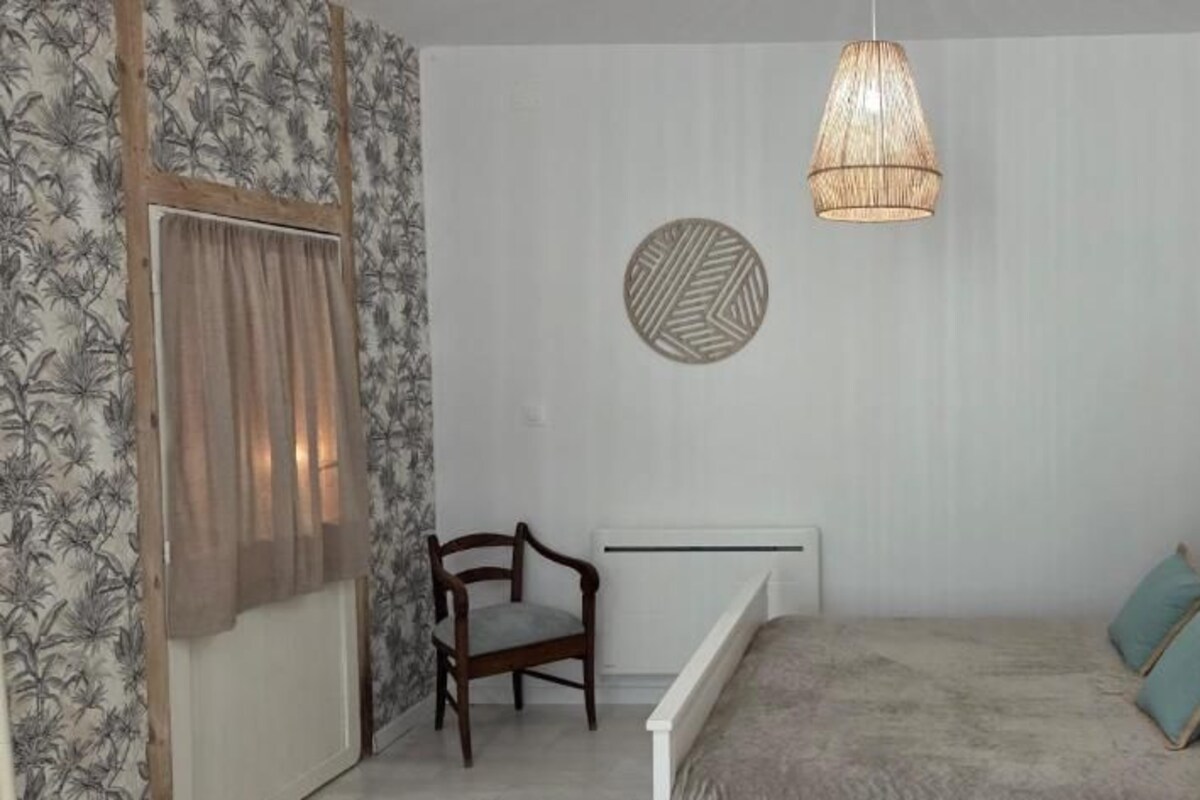 Quarto com cama, poltrona, radiador e arte decorativa nas paredes.