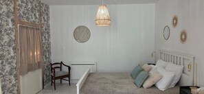 A bedroom with a bed, a chair, a radiator, and decorative wall art.