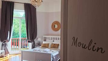 Une chambre à coucher avec un lit, une fenêtre avec des rideaux, une table de chevet et un mur sur lequel est écrit le mot « Moulin ».