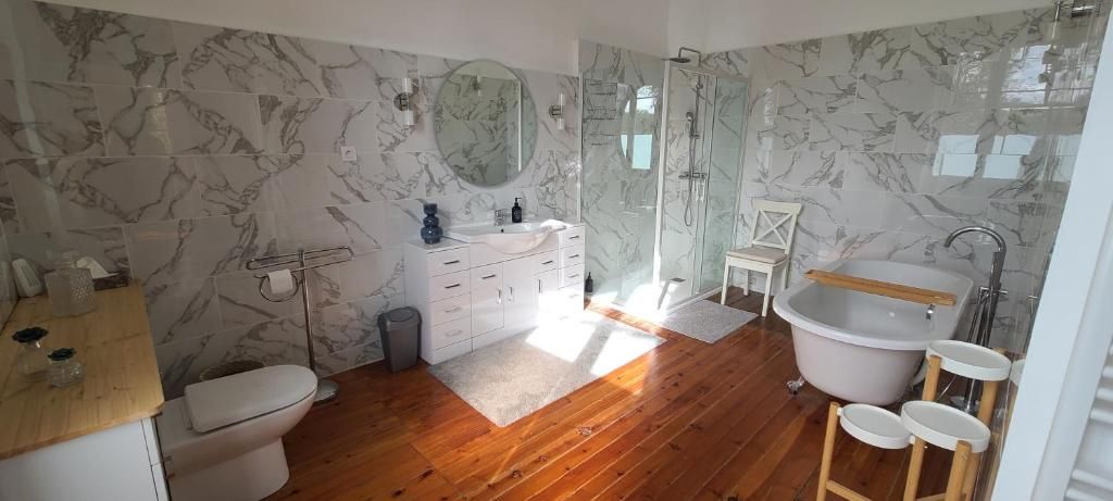 Un baño con salpicadero de mármol, una bañera independiente, un tocador con espejo y una zona de ducha.