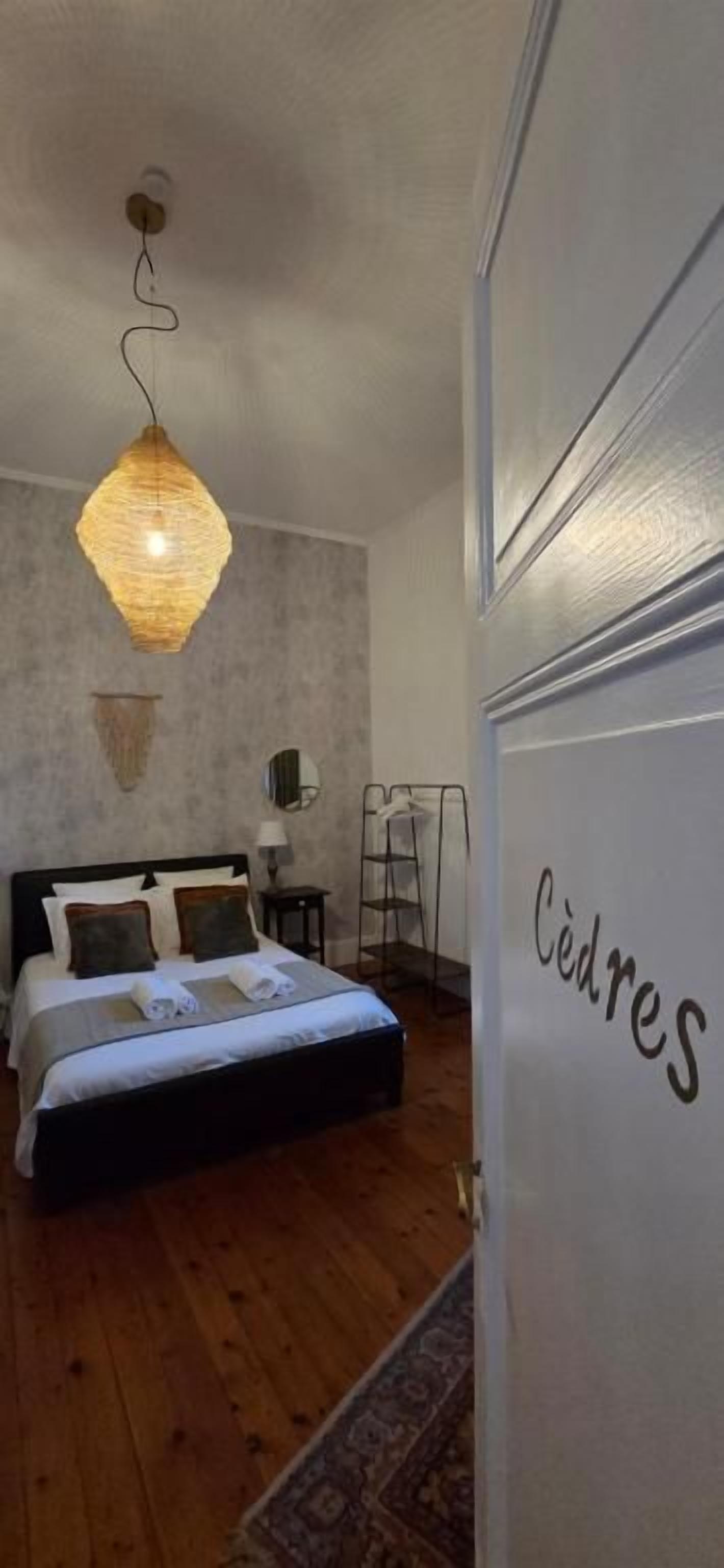 Un dormitorio con cama, mesita de noche, lámpara y una lámpara colgante.