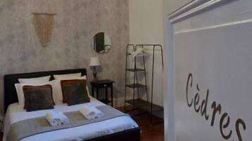Un dormitorio con cama, mesita de noche, lámpara y una lámpara colgante.