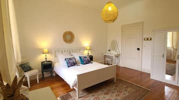 A bedroom with a bed, bedside tables, a mirror, a wardrobe, and a hanging light fixture.