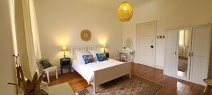 Un dormitorio con cama, mesitas de noche, espejo, armario e iluminación colgante.