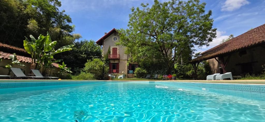 Ein Swimmingpool mit klarem, blauem Wasser, umgeben von Liegestühlen und einem Gebäude mit rotem Dach.