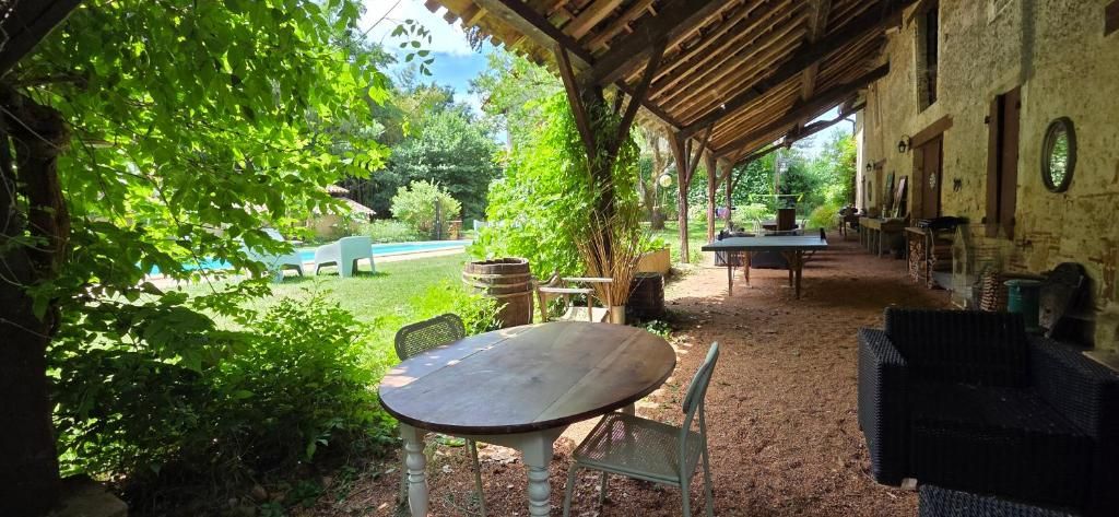 Un espace extérieur aménagé en terrasse, avec une table et des chaises, entouré de verdure et offrant une vue sur une piscine.