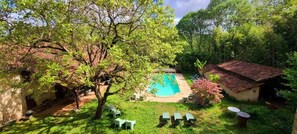 A backyard with a swimming pool, surrounded by trees and a small building.