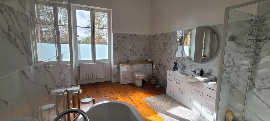 Une salle de bain avec une baignoire, des toilettes, un lavabo et une grande fenêtre.