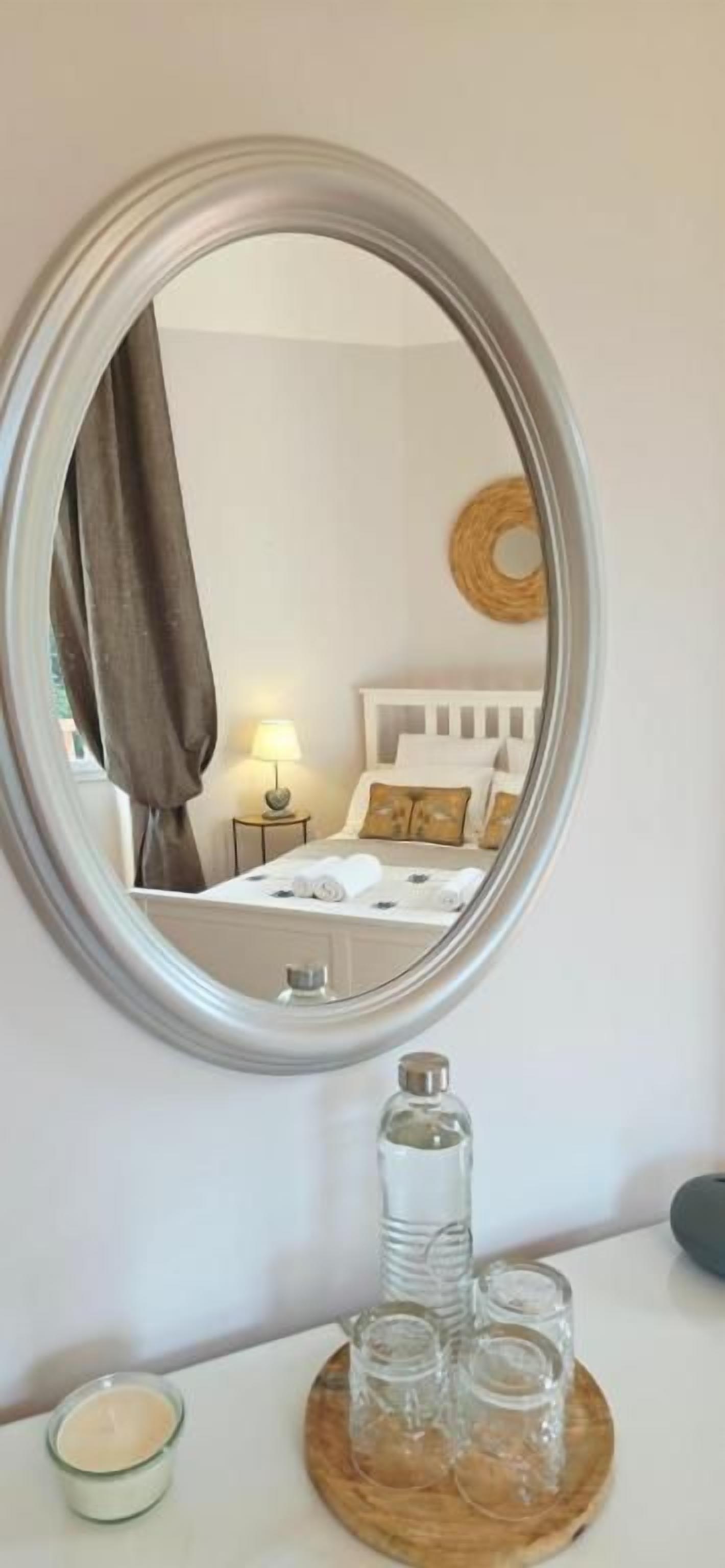 Ein Zimmer mit einem Bett, einem Nachttisch mit Lampe und einem Spiegel an der Wand.