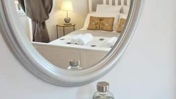 Ein Zimmer mit einem Bett, einem Nachttisch mit Lampe und einem Spiegel an der Wand.