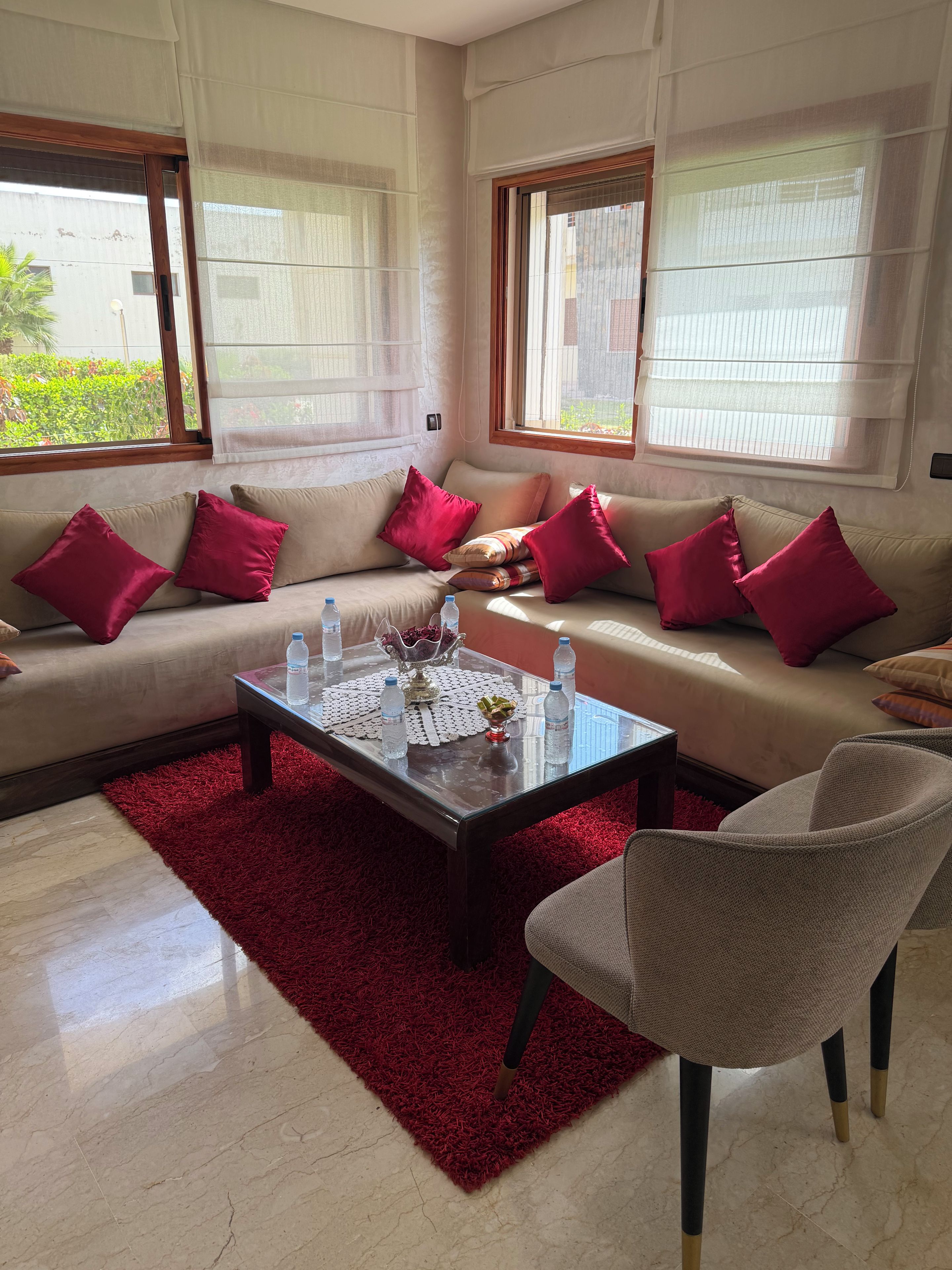 Un salon avec un canapé, des fauteuils, une table basse et un tapis rouge.