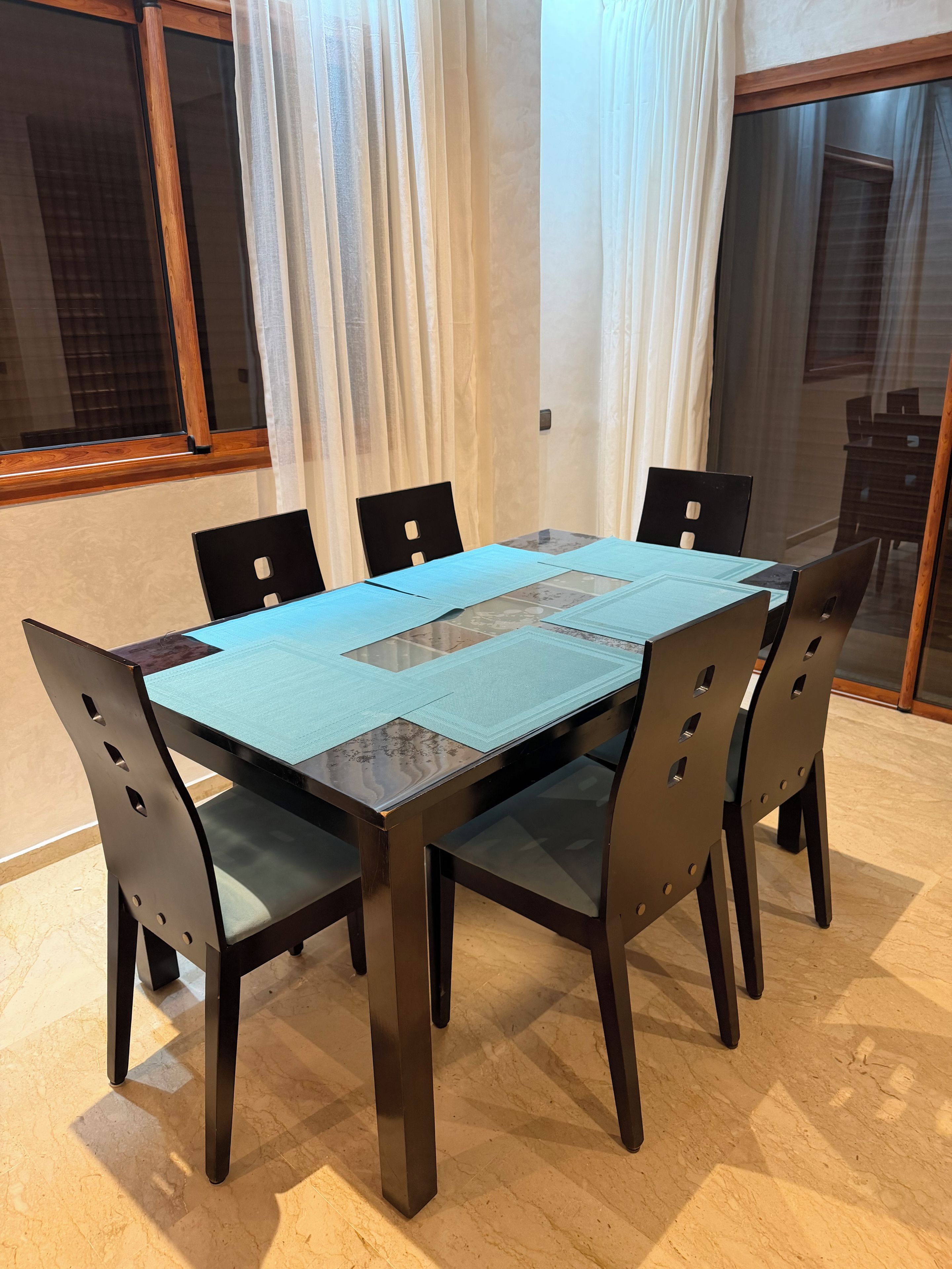 Een eethoek met een rechthoekige tafel, zes stoelen en een glazen scheidingswand.