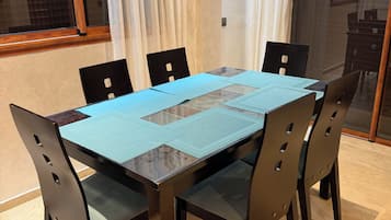 Een eethoek met een rechthoekige tafel, zes stoelen en een glazen scheidingswand.