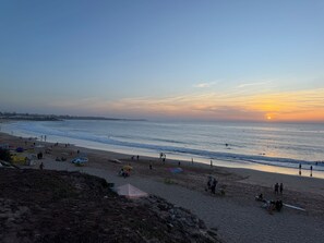 A beach with people, tents, and a sunset.