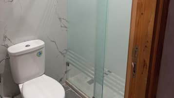 Ein Badezimmer mit Toilette, einer Duschkabine aus Glas und einer Wand mit Marmoroptik.