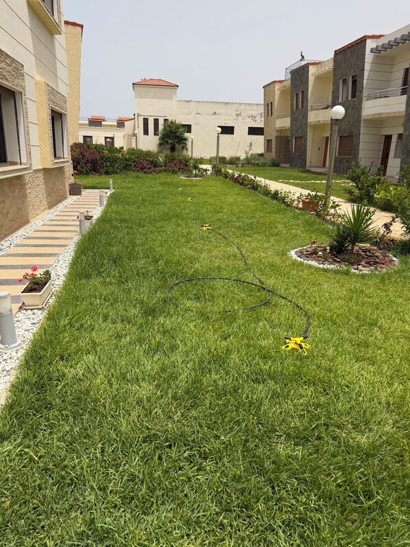 A well-maintained lawn with a pathway leading to a building with multiple floors and balconies.