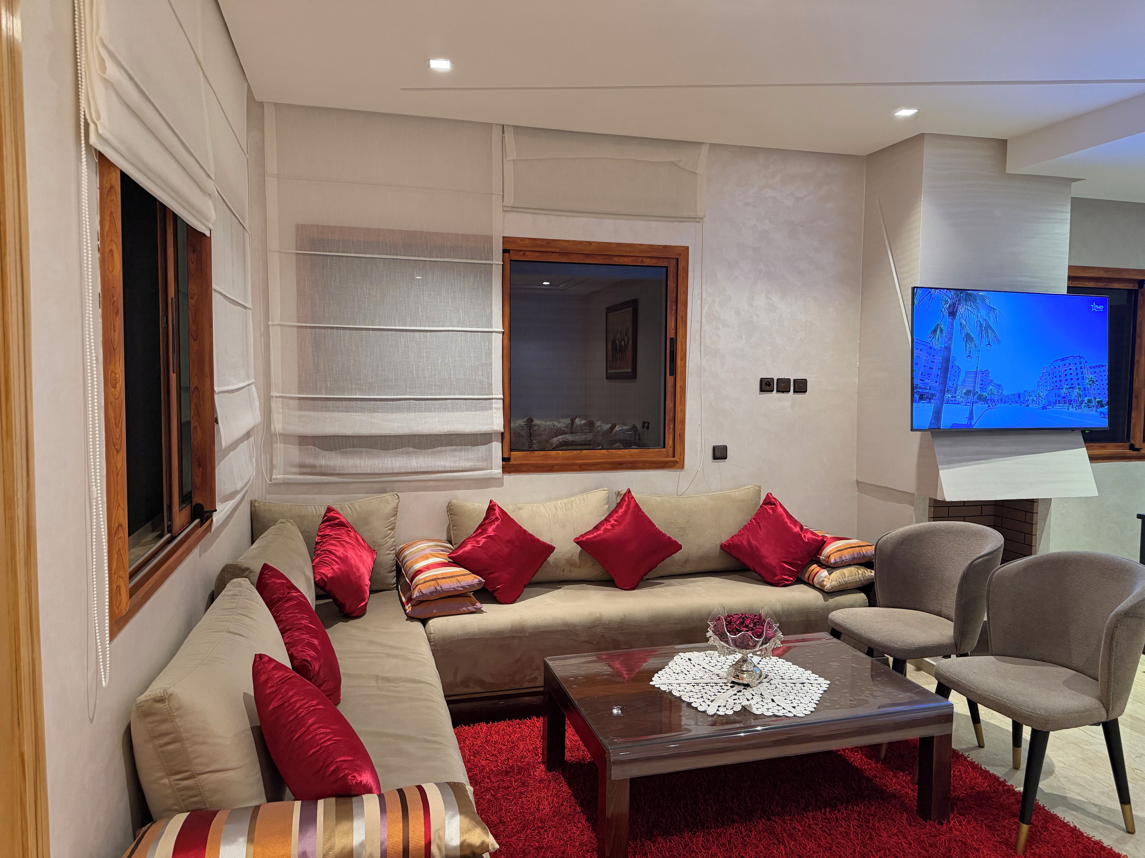 Ein stilvolles Wohnzimmer mit einer Couch, Sesseln, einem Couchtisch und einem Fernseher.