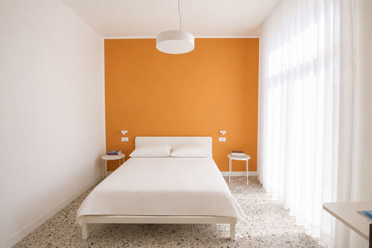 Un dormitorio con una cama, dos mesitas de noche y una lámpara colgante.