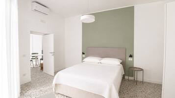 Una habitación de hotel con una cama, una mesita de noche, una lámpara y vistas a un comedor.