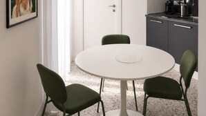 Cozinha moderna com mesa redonda e cadeiras, micro-ondas e cafeteira.
