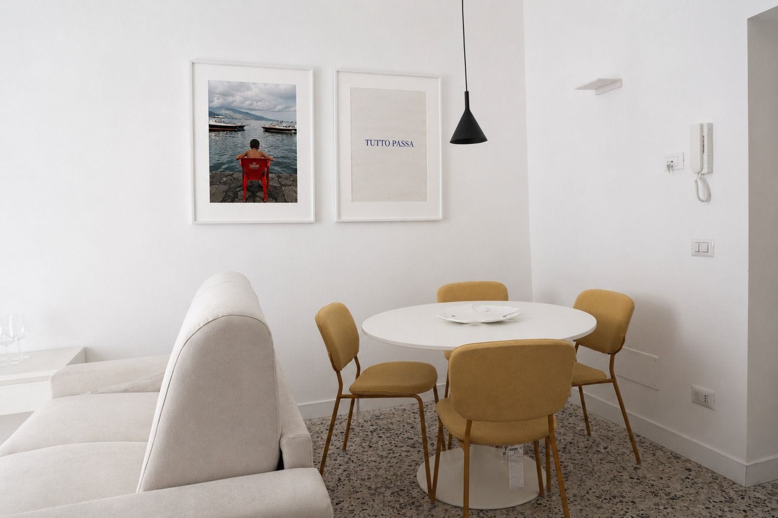 Un comedor moderno con una mesa redonda, cuatro sillas y dos cuadros en la pared.