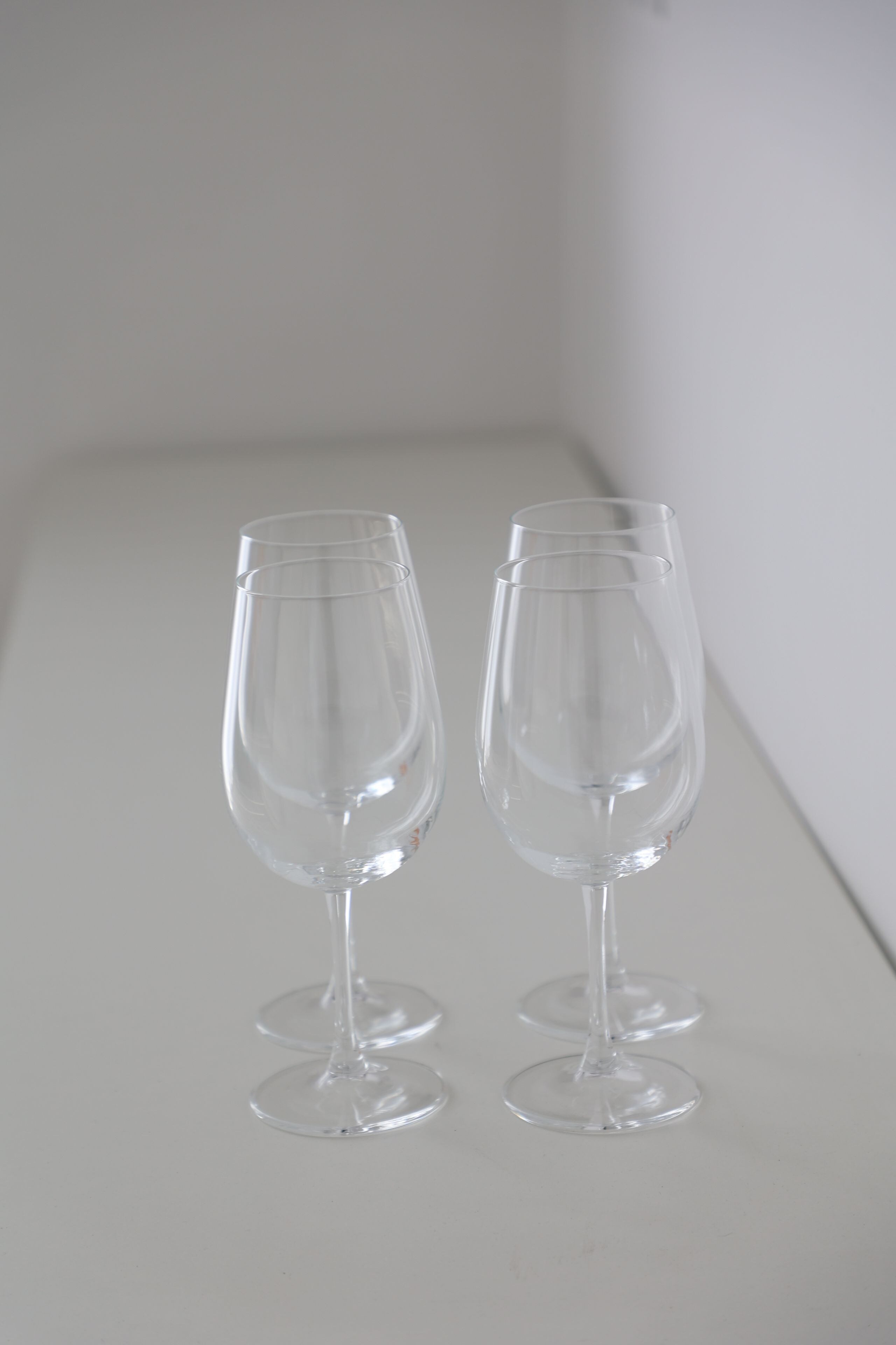 Dos copas de vino transparentes sobre una superficie blanca.