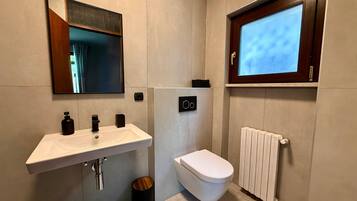 Un bagno moderno con lavandino bianco, vaso, specchio e finestra.