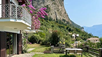 Ein Wohnhaus mit Balkon, einem gepflasterten Weg und Blick auf eine Berglandschaft.