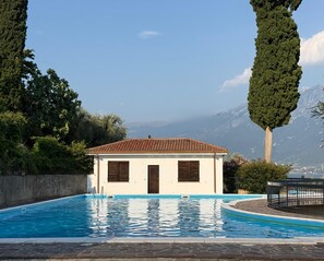 Un pequeño edificio con piscina, rodeado de árboles y montañas.