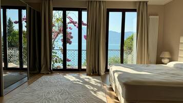 Une chambre avec un grand lit, une vue sur la mer et un balcon agrémenté de fleurs.