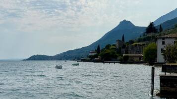 A calm lake with boats, a mountain in the background, and buildings along the shore.