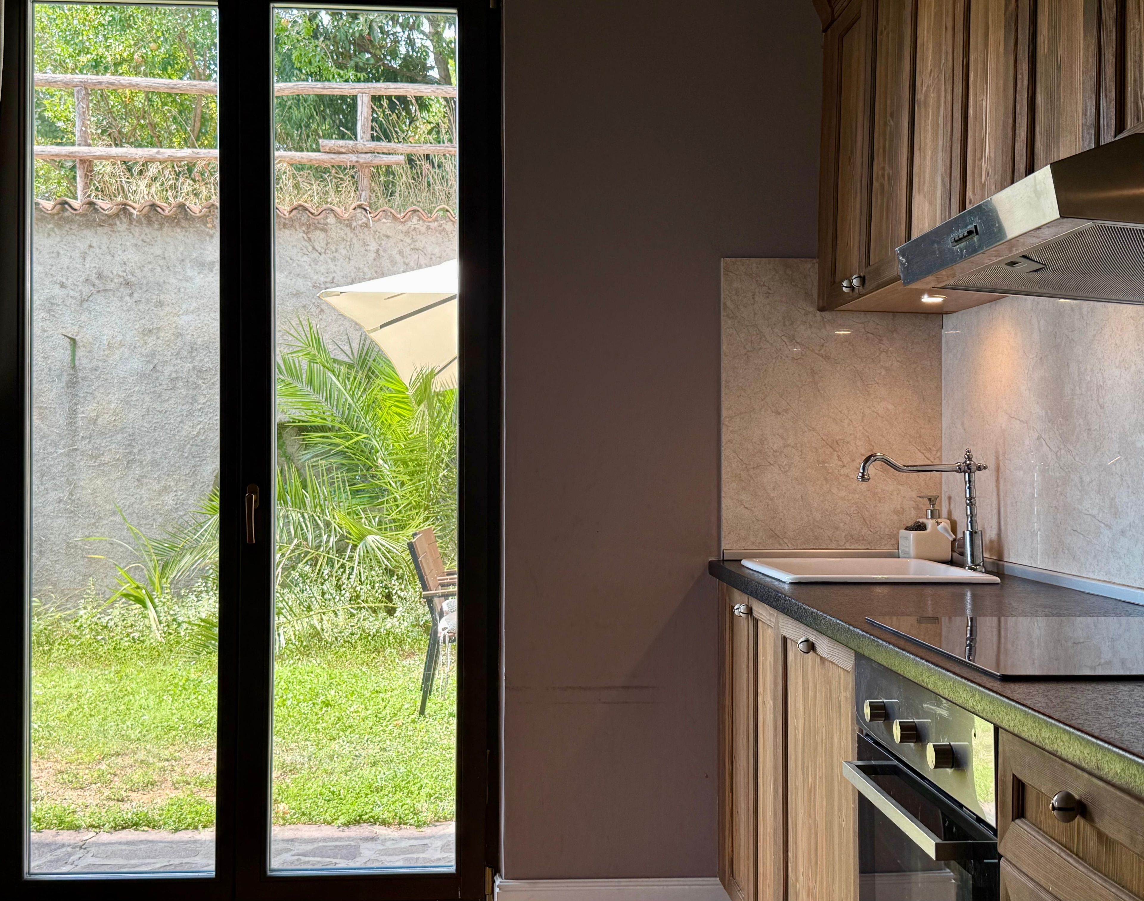 A modern kitchen with a large window, a sink, and wooden cabinets.