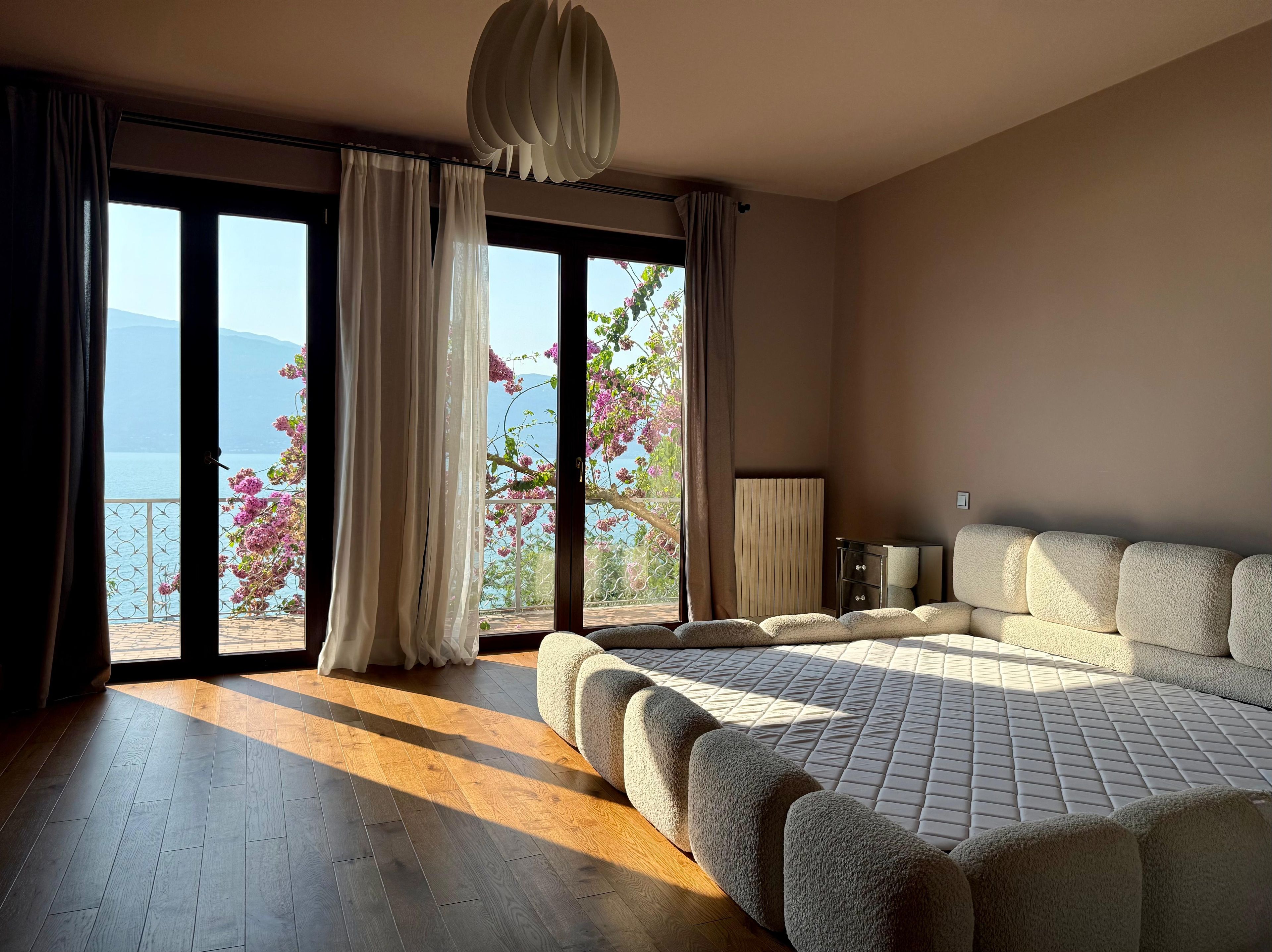 Una camera da letto con un letto grande, vista mare e un balcone fiorito.