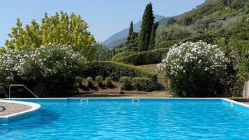 Une piscine à l’eau d’un bleu cristallin, entourée d’une végétation luxuriante et dominée par un paysage montagneux.