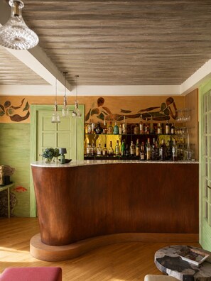 A bar area with a curved wooden counter, hanging pendant lights, and a wall mural. - Romantic Villa on Lake Millstatt (Seeboden)