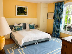 A bedroom with a bed, a nightstand, a lamp, a wardrobe, a window with curtains, and a painting on the wall. - Romantic Villa on Lake Millstatt (Seeboden)