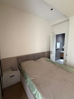 Ein Schlafzimmer mit einem Einzelbett, einem Nachttisch und einer Tür zu einem Badezimmer.