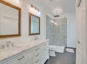 A bathroom with a marble vanity, a toilet, and a glass shower enclosure. - Heated Saltwater Pool + Hot Tub + Tiki Bar. Only minutes to Downtown & Beaches (Vero Beach)