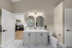 Un baño moderno con tocador de doble lavabo, inodoro y un espejo grande sobre el tocador.