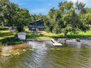 Una propiedad residencial con un estanque, un muelle y una casa con un patio.