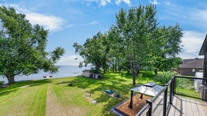 A residential property with a deck, a lawn, and a view of a lake. - Lakeside Modern Retreat in PEC (Prince Edward)