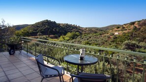 Eine Terrasse mit Tisch und Stühlen mit Blick auf eine hügelige Landschaft.
