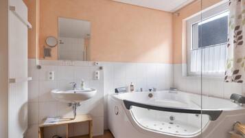 Ein modernes Badezimmer mit einer Badewanne, einem Waschbecken und einem Spiegel.