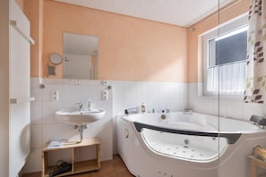Un baño moderno con bañera, lavamanos y espejo.