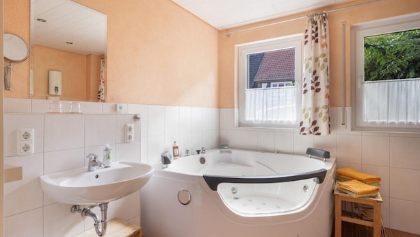 Een badkamer met een wastafel, bad en een raam met uitzicht op een huis.