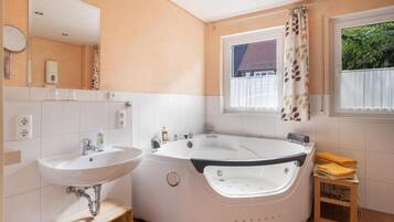Ein Badezimmer mit Waschbecken, Badewanne und einem Fenster mit Blick auf ein Haus.