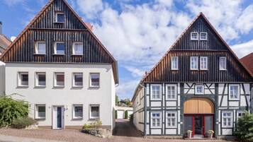 Zwei traditionelle Fachwerkhäuser mit zahlreichen Fenstern und blauem Himmel.