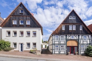 Zwei traditionelle Fachwerkhäuser mit zahlreichen Fenstern und blauem Himmel.